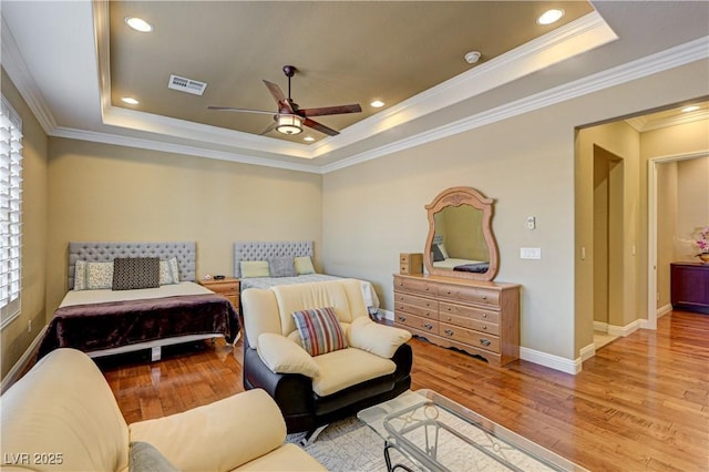 bedroom featuring a raised ceiling, wood finished floors, crown molding, baseboards, and ceiling fan
