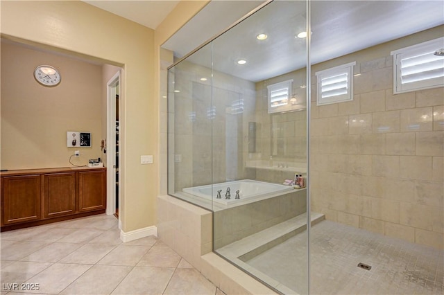 bathroom featuring tile patterned flooring, a tile shower, a bath, and baseboards