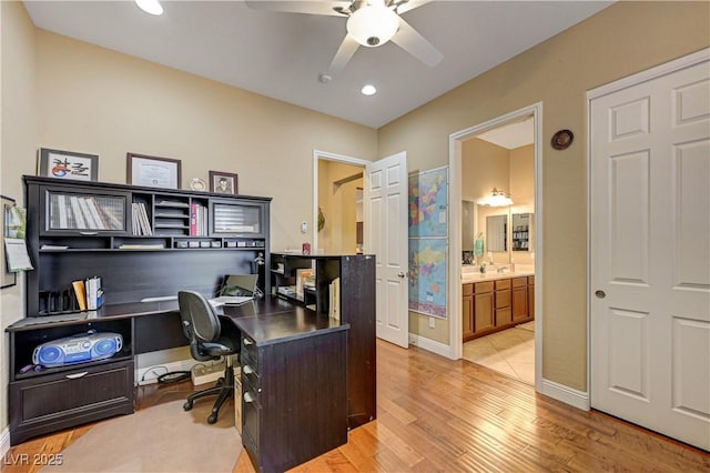 office featuring a ceiling fan, light wood-style flooring, baseboards, recessed lighting, and a sink