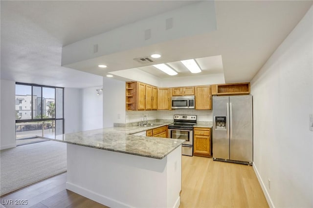 3930 University Center Dr Unit 311, Las Vegas, NV 89119 - kitchen featuring appliances with stainless steel finishes, open shelves, a peninsula, light stone countertops, and baseboards