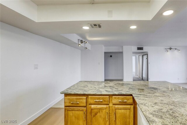 3930 University Center Dr Unit 311, Las Vegas, NV 89119 - kitchen with light stone counters, recessed lighting, baseboards, brown cabinets, and light wood-style flooring