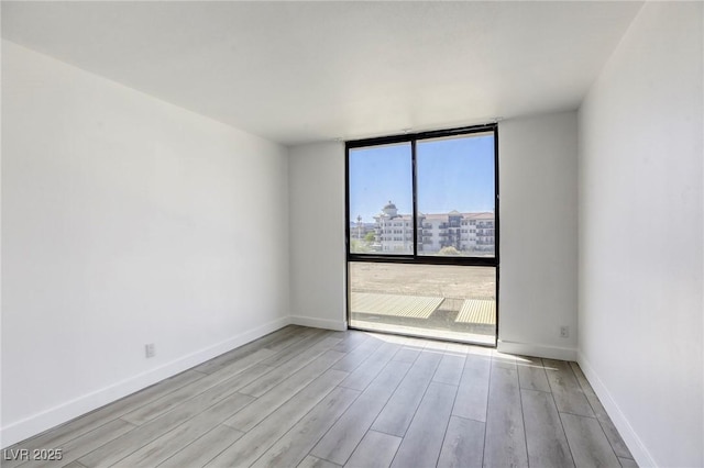 3930 University Center Dr Unit 312, Las Vegas, NV 89119 - empty room featuring wood finished floors, a wall of windows, and baseboards