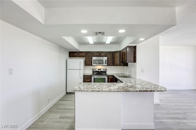 3930 University Center Dr Unit 312, Las Vegas, NV 89119 - kitchen featuring stainless steel appliances, light stone countertops, dark brown cabinetry, baseboards, and a peninsula