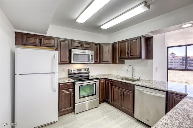 3930 University Center Dr Unit 312, Las Vegas, NV 89119 - kitchen with appliances with stainless steel finishes, a sink, dark brown cabinetry, and light stone counters