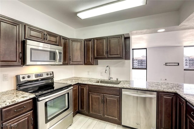 3930 University Center Dr Unit 312, Las Vegas, NV 89119 - kitchen featuring stainless steel appliances, a sink, dark brown cabinetry, and light stone counters