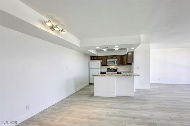 3930 University Center Dr Unit 312, Las Vegas, NV 89119 - kitchen with stainless steel appliances, a sink, dark brown cabinets, light wood finished floors, and baseboards