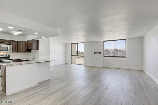 3930 University Center Dr Unit 312, Las Vegas, NV 89119 - kitchen with appliances with stainless steel finishes, open floor plan, a sink, dark brown cabinets, and light wood finished floors