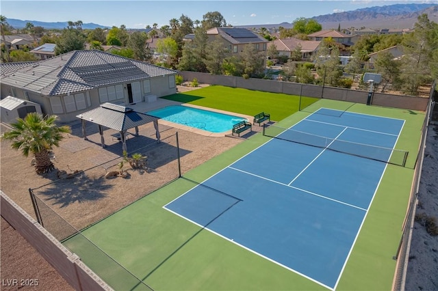 view of tennis court featuring fence, a mountain view, and a residential view