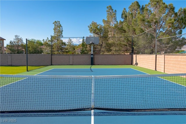 view of basketball court with basketball hoop and fence