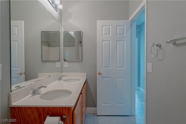 full bath featuring tile patterned floors, baseboards, and double vanity