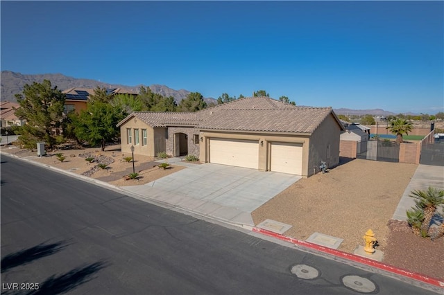 8228 Fulton Ranch St, Las Vegas, NV 89131 - view of front facade with a gate, a mountain view, a garage, stucco siding, and a tiled roof