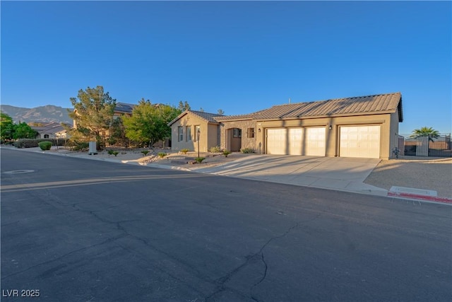view of front of home with a tile roof, driveway, an attached garage, and stucco siding