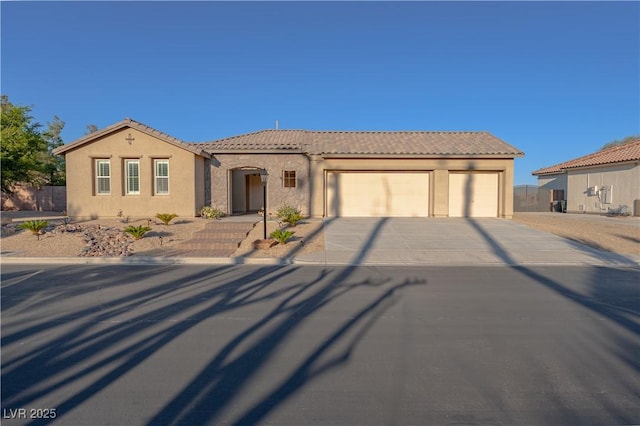 mediterranean / spanish-style house featuring an attached garage, concrete driveway, a tiled roof, and stucco siding