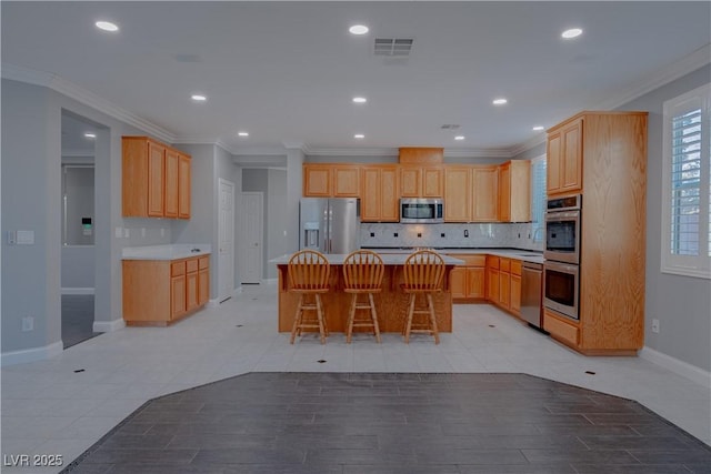kitchen with appliances with stainless steel finishes, tasteful backsplash, a breakfast bar, baseboards, and a center island