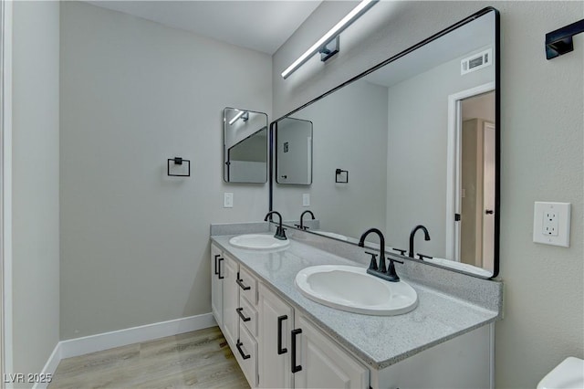 bathroom with wood finished floors, double vanity, and baseboards