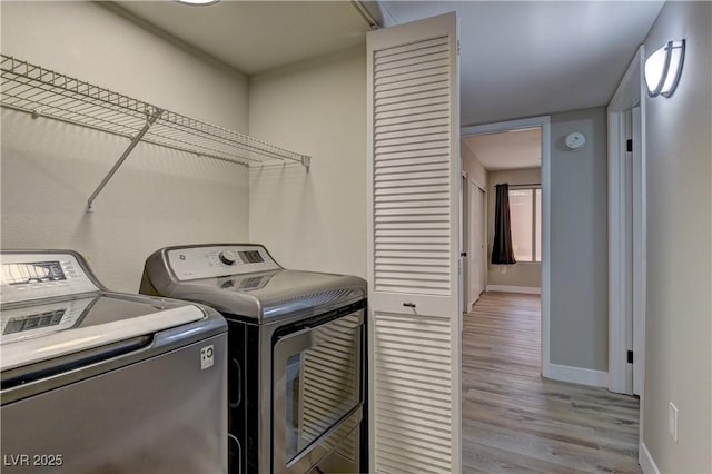 laundry area featuring independent washer and dryer, baseboards, and light wood-style floors