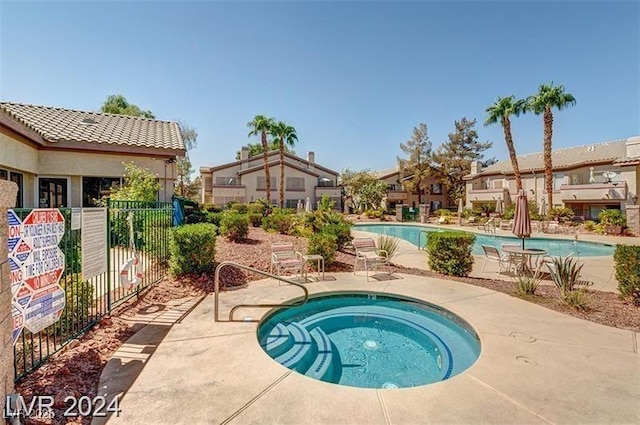 community pool featuring a hot tub, fence, and a patio