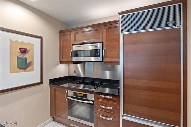 125 E Harmon Ave Unit 321, Las Vegas, NV 89109 - kitchen with appliances with stainless steel finishes, dark countertops, baseboards, and brown cabinetry