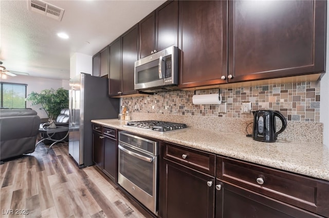 4650 Ranch House Rd Unit 86, North Las Vegas, NV 89031 - kitchen with stainless steel appliances, dark brown cabinets, decorative backsplash, a ceiling fan, and light wood-style flooring