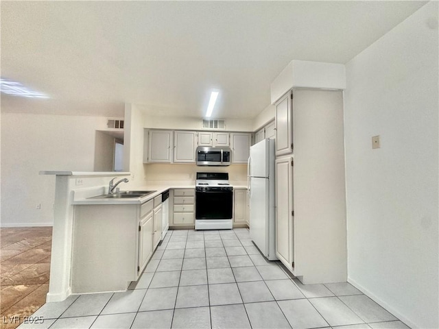 kitchen with white appliances, a sink, light countertops, light tile patterned floors, and a peninsula