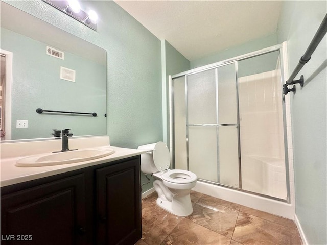 full bathroom with a stall shower, toilet, vanity, a textured wall, and baseboards