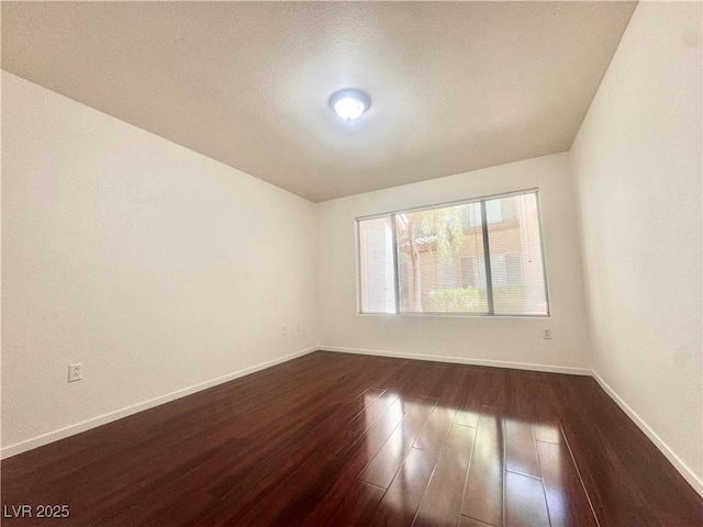 empty room with dark wood-style floors and baseboards