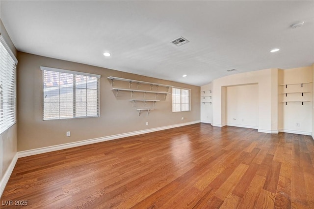 unfurnished living room with wood finished floors, baseboards, and recessed lighting