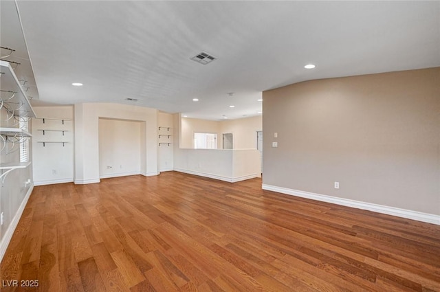empty room with wood finished floors, baseboards, and recessed lighting