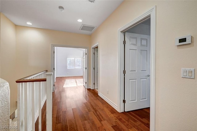 hallway with dark wood-style floors, baseboards, an upstairs landing, and recessed lighting