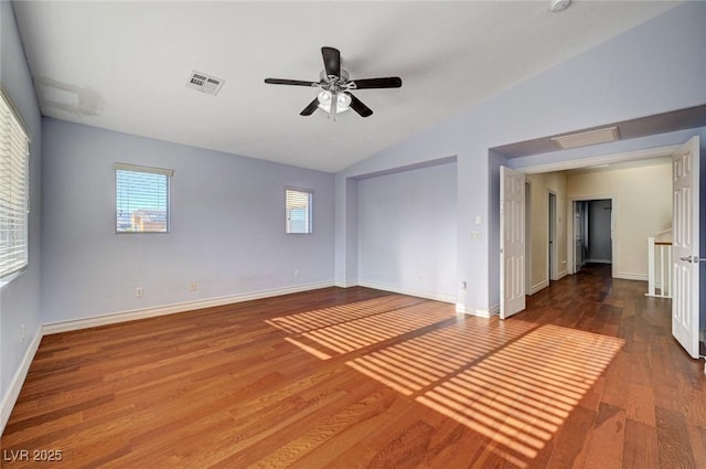 empty room with lofted ceiling, plenty of natural light, wood finished floors, ceiling fan, and baseboards