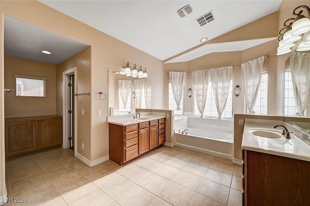 full bathroom with vaulted ceiling, two vanities, a bath, tile patterned floors, and baseboards