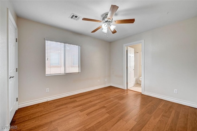 unfurnished bedroom with wood finished floors, baseboards, connected bathroom, and a ceiling fan