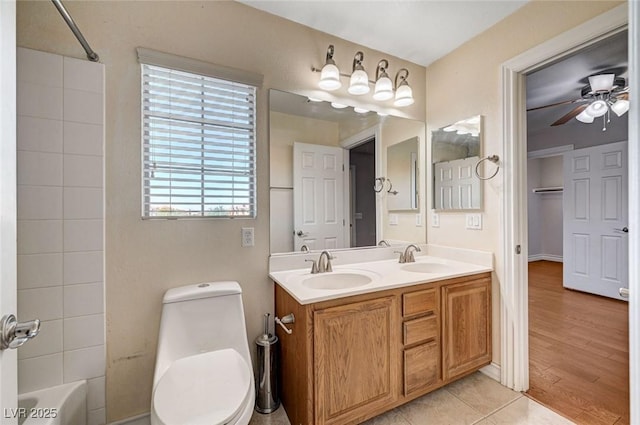 full bath featuring toilet, wood finished floors, bathing tub / shower combination, double vanity, and a ceiling fan