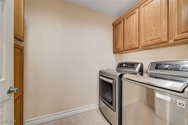 clothes washing area featuring washing machine and clothes dryer, cabinet space, baseboards, and light tile patterned flooring