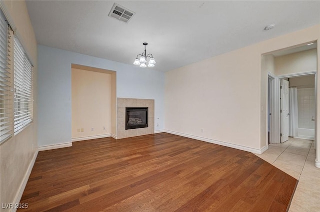 unfurnished living room featuring wood finished floors, a chandelier, a fireplace, and baseboards