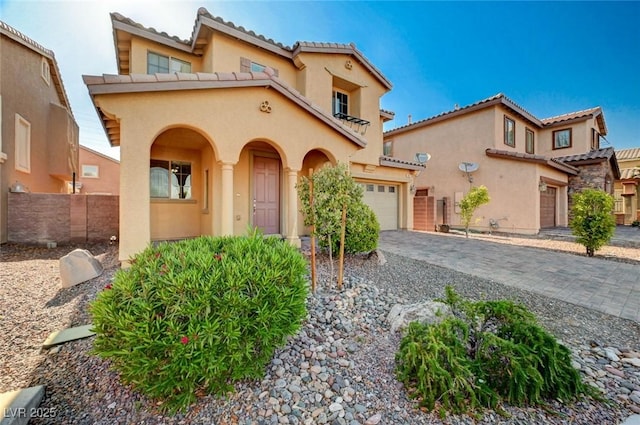 mediterranean / spanish house with stucco siding, a tile roof, driveway, a garage, and fence
