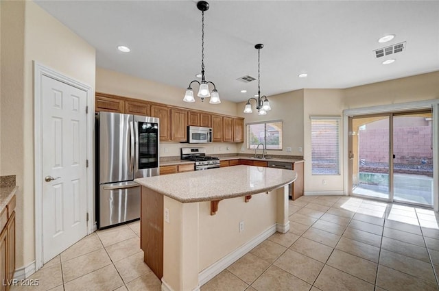 kitchen featuring appliances with stainless steel finishes, a sink, a chandelier, light tile patterned flooring, and a center island