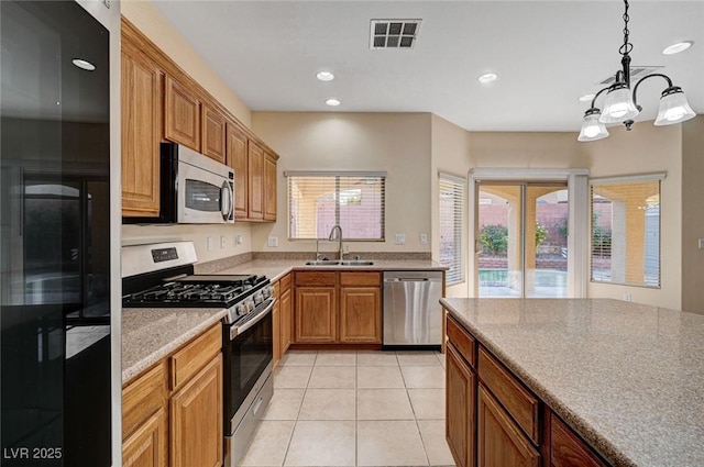 kitchen with appliances with stainless steel finishes, a sink, light tile patterned floors, recessed lighting, and decorative light fixtures