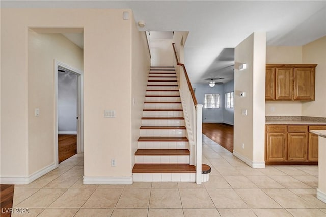 stairway with tile patterned floors, ceiling fan, and baseboards