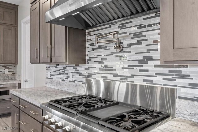 7477 Triple Knot Ct, Las Vegas, NV 89113 - kitchen with backsplash, wall chimney range hood, stainless steel gas range, and light stone counters