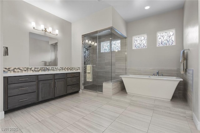 7477 Triple Knot Ct, Las Vegas, NV 89113 - full bathroom featuring vanity, a freestanding bath, a stall shower, tile patterned floors, and tile walls