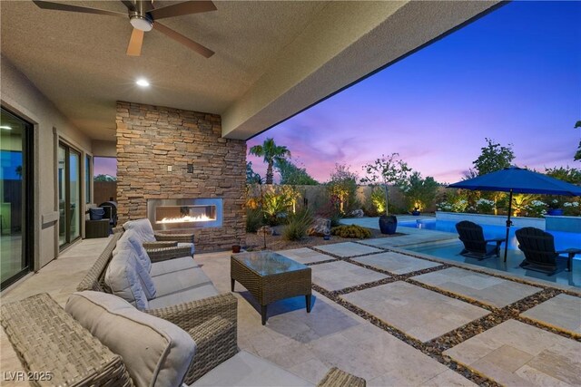 7477 Triple Knot Ct, Las Vegas, NV 89113 - patio terrace at dusk featuring a patio area, an outdoor living space with a fireplace, an outdoor pool, and a ceiling fan
