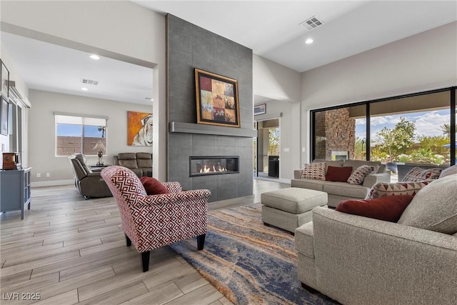 7477 Triple Knot Ct, Las Vegas, NV 89113 - living room featuring light wood-type flooring, recessed lighting, a towering ceiling, a tile fireplace, and baseboards