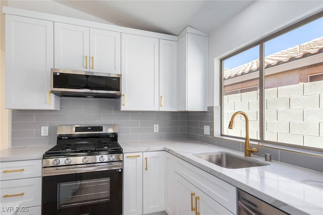 kitchen with stainless steel appliances, a sink, white cabinets, and decorative backsplash