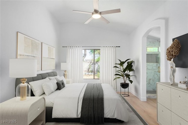 bedroom featuring light wood-style flooring, arched walkways, connected bathroom, baseboards, and lofted ceiling