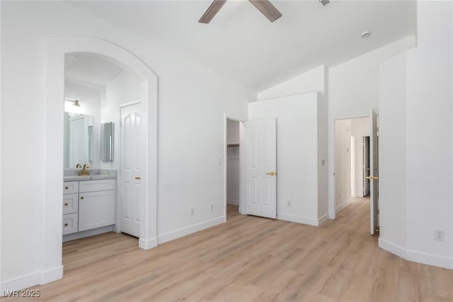 unfurnished bedroom featuring light wood-style floors, a sink, baseboards, and high vaulted ceiling