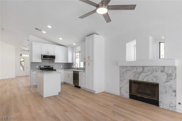 kitchen featuring appliances with stainless steel finishes, a ceiling fan, vaulted ceiling, a kitchen island, and a sink