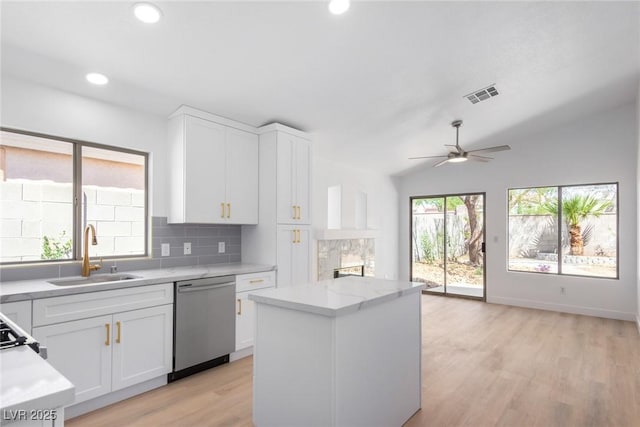 kitchen featuring dishwasher, a sink, light wood-style flooring, backsplash, and white cabinets