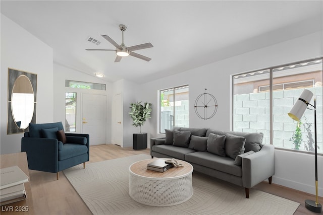 living room featuring a ceiling fan, light wood-type flooring, vaulted ceiling, and baseboards