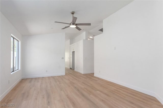 empty room with a ceiling fan, light wood finished floors, baseboards, and lofted ceiling